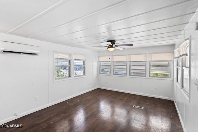 spare room featuring dark wood-type flooring, a wall mounted air conditioner, and ceiling fan