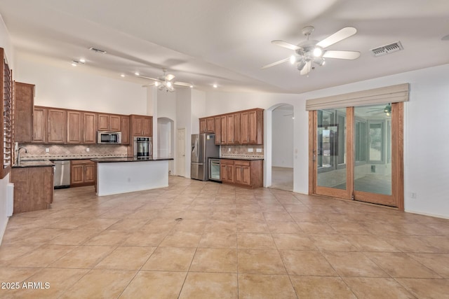 kitchen with stainless steel appliances, arched walkways, visible vents, and dark countertops