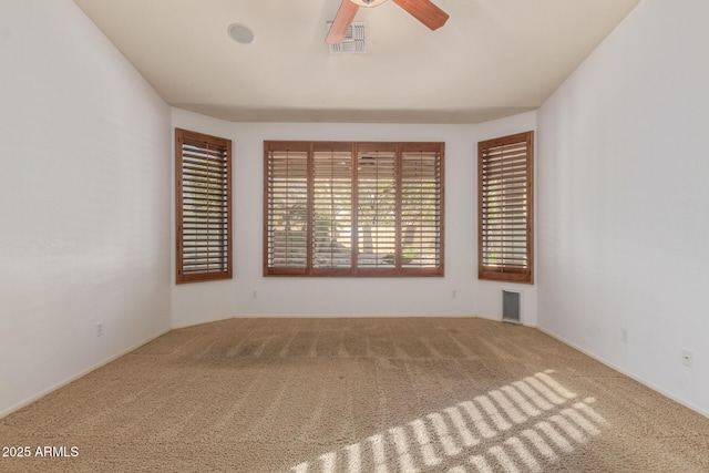 unfurnished room with carpet, visible vents, and a ceiling fan