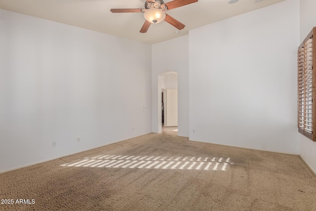 spare room featuring carpet floors, arched walkways, and a ceiling fan