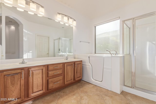 bathroom with tile patterned flooring, a sink, a bath, and a shower stall