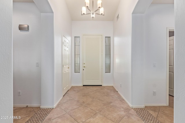 entryway with light tile patterned floors, visible vents, arched walkways, and a notable chandelier