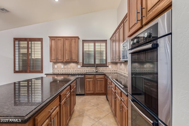 kitchen with a sink, visible vents, vaulted ceiling, appliances with stainless steel finishes, and decorative backsplash