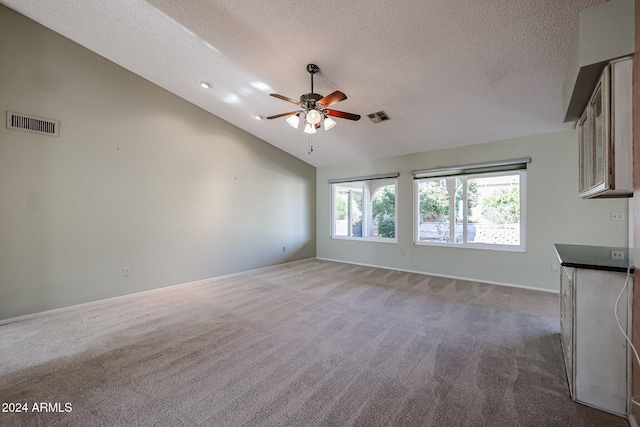 unfurnished living room with a textured ceiling, ceiling fan, carpet flooring, and vaulted ceiling