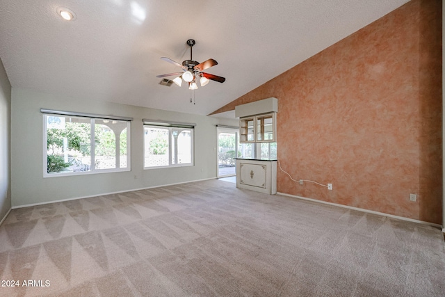 empty room featuring a textured ceiling, ceiling fan, light carpet, and vaulted ceiling