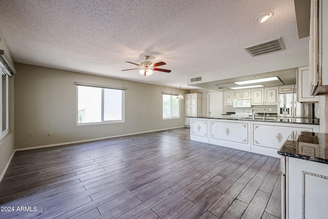 kitchen featuring white cabinetry, stainless steel fridge with ice dispenser, hardwood / wood-style floors, and a textured ceiling