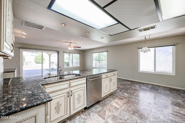 kitchen with pendant lighting, stainless steel dishwasher, dark stone counters, and sink