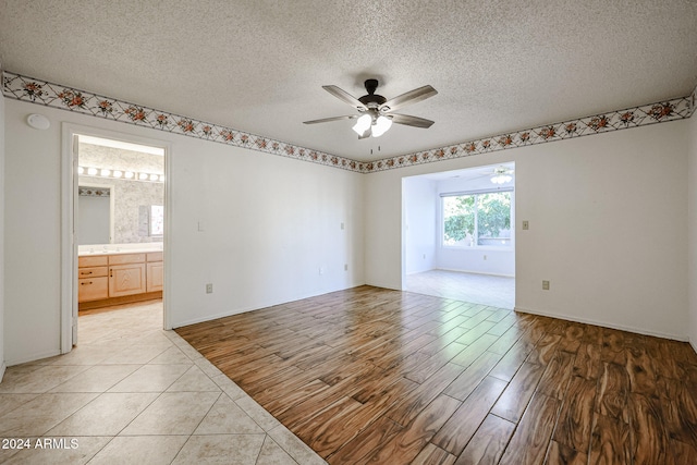 empty room featuring ceiling fan, light hardwood / wood-style floors, and a textured ceiling