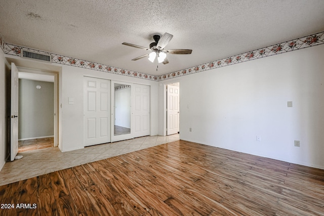 unfurnished bedroom with a closet, ceiling fan, light hardwood / wood-style flooring, and a textured ceiling