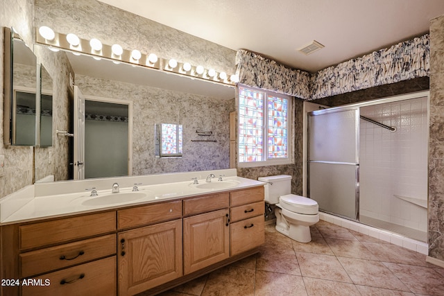 bathroom featuring tile patterned flooring, vanity, toilet, and a shower with door