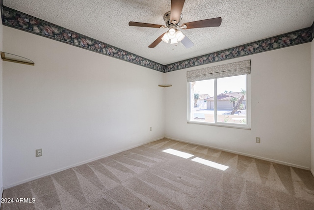 carpeted empty room with ceiling fan and a textured ceiling