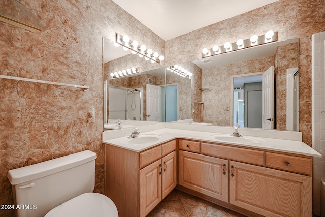 bathroom featuring tile patterned flooring, vanity, toilet, and a shower with door