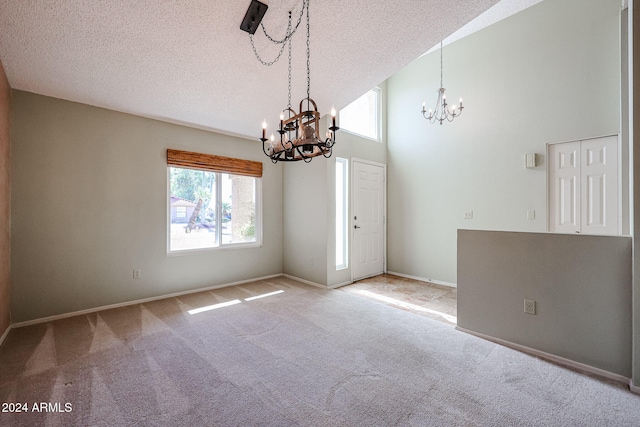 carpeted spare room featuring a notable chandelier, a textured ceiling, and a high ceiling