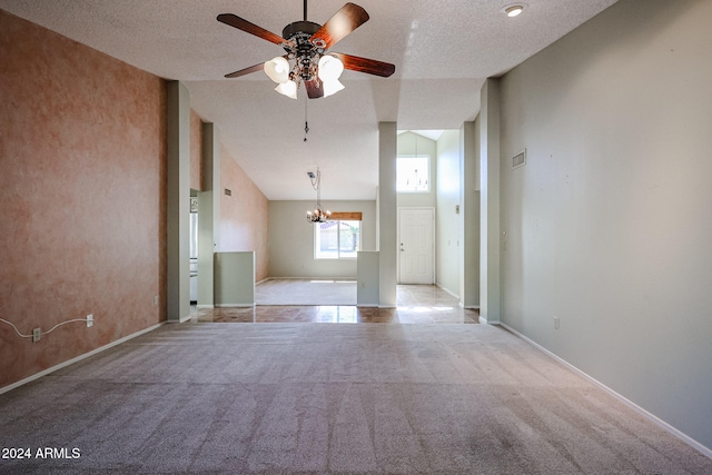 carpeted empty room featuring ceiling fan with notable chandelier, a textured ceiling, and high vaulted ceiling