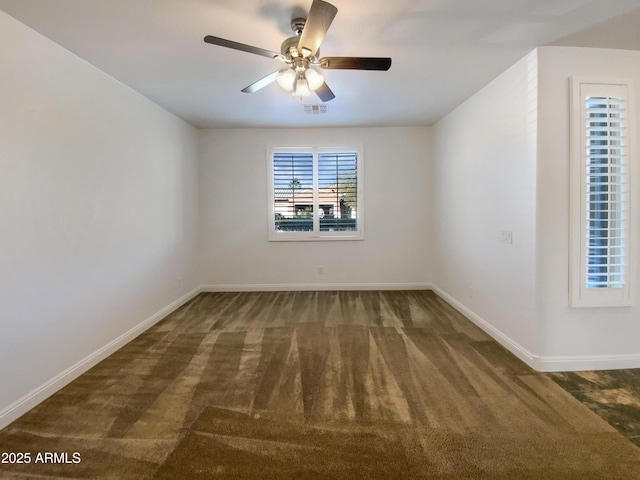 spare room with ceiling fan and dark colored carpet