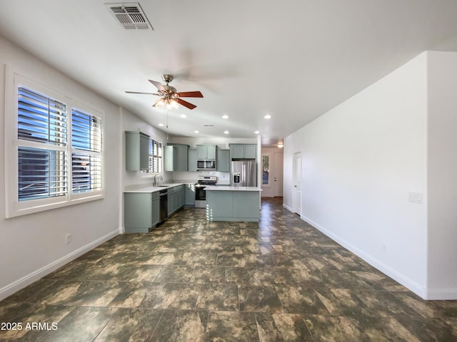 kitchen featuring appliances with stainless steel finishes, a center island, sink, gray cabinets, and ceiling fan