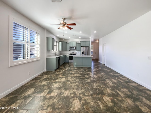 kitchen featuring ceiling fan, sink, a kitchen island, stainless steel appliances, and gray cabinets