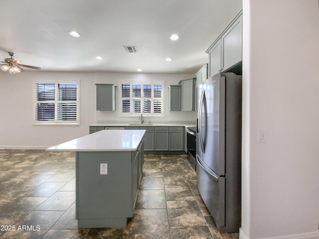 kitchen with a center island, appliances with stainless steel finishes, sink, ceiling fan, and gray cabinets