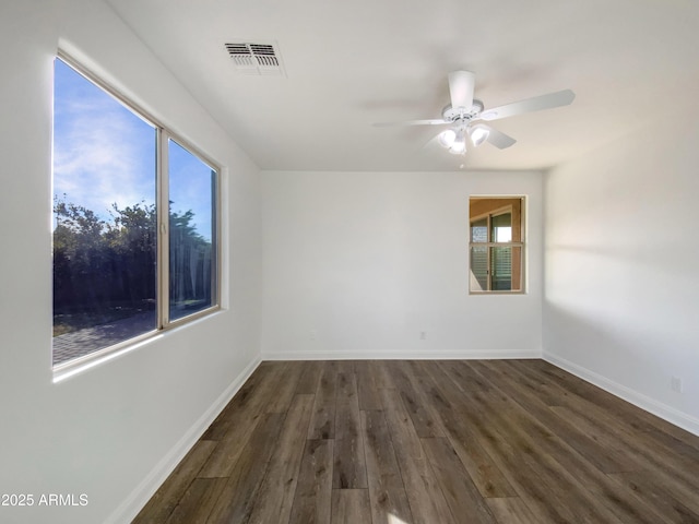 spare room with ceiling fan, a wealth of natural light, and dark hardwood / wood-style flooring