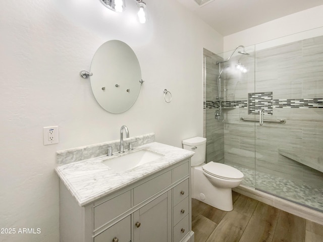 bathroom featuring vanity, a shower with shower door, and toilet