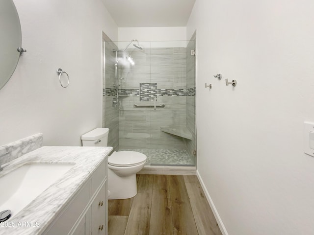 bathroom featuring toilet, a shower with shower door, and vanity