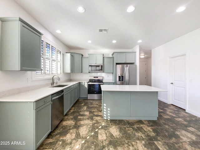 kitchen with sink, a kitchen island, gray cabinetry, and stainless steel appliances