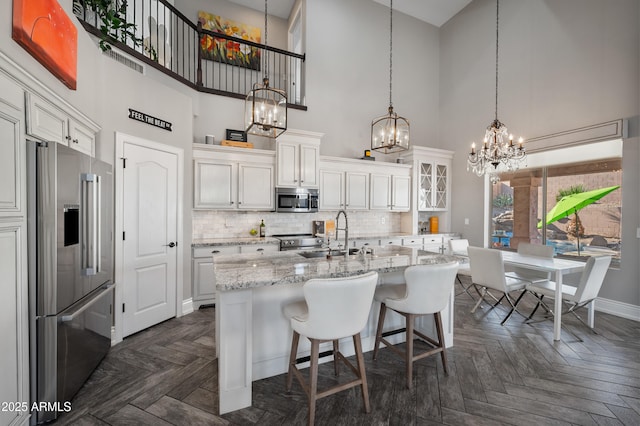 1834 W Nighthawk Way, Phoenix, AZ 85045 - kitchen with appliances with stainless steel finishes, a towering ceiling, a chandelier, white cabinets, and baseboards