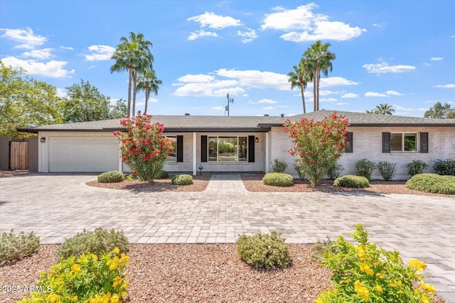 ranch-style house featuring decorative driveway and a garage
