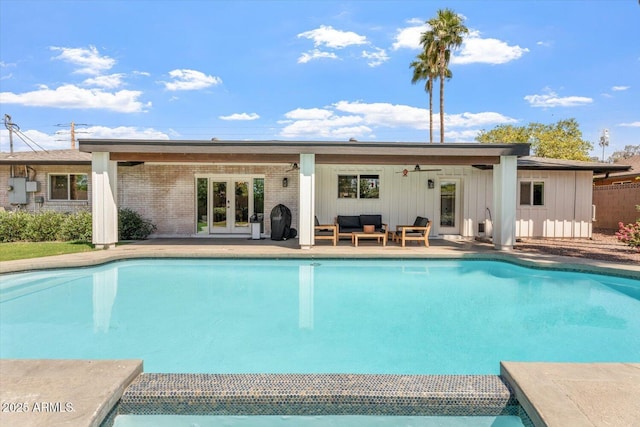 rear view of property featuring brick siding, outdoor lounge area, an outdoor pool, and french doors