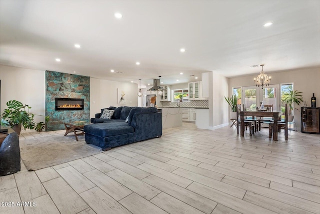 living room featuring recessed lighting, an inviting chandelier, a tile fireplace, and light wood-type flooring