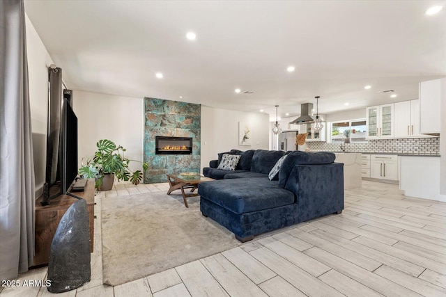living area featuring a tiled fireplace, recessed lighting, and light wood-style flooring