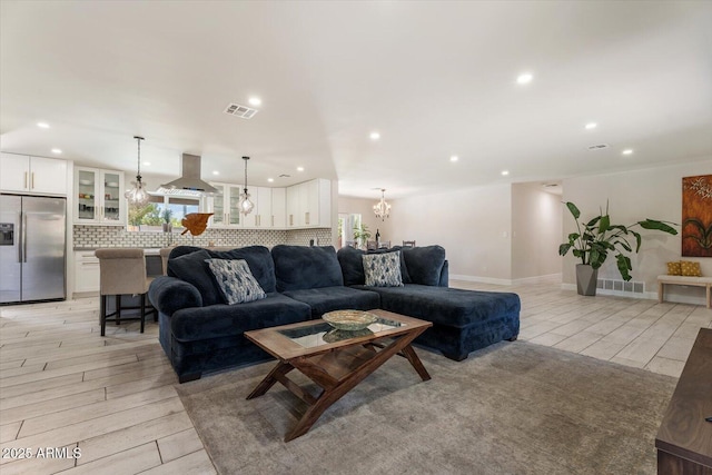 living area with an inviting chandelier, recessed lighting, light wood-style floors, and visible vents