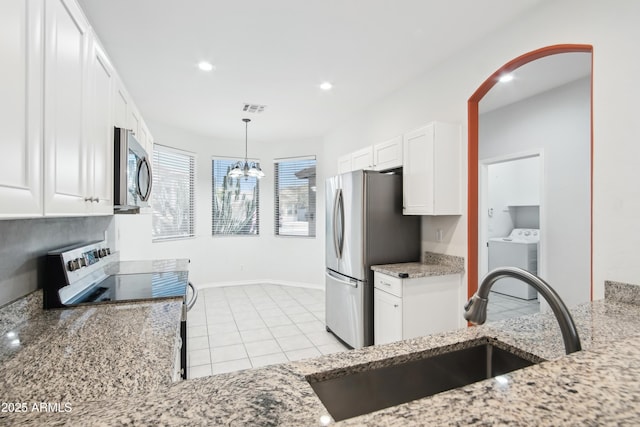 kitchen featuring washer / clothes dryer, light stone counters, white cabinets, stainless steel appliances, and a sink