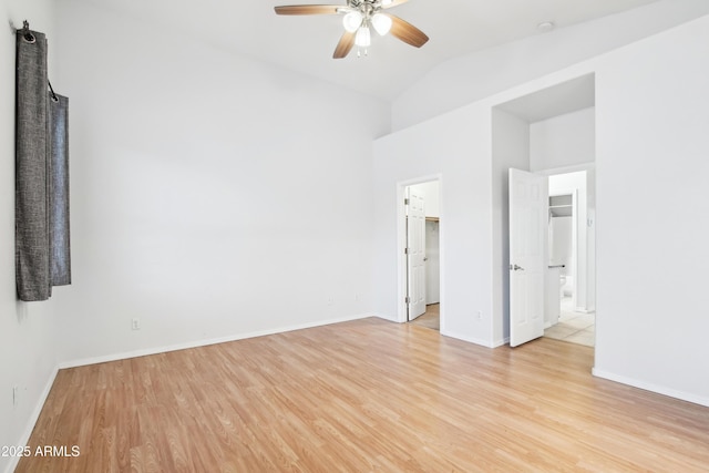 spare room with light wood-type flooring, ceiling fan, baseboards, and vaulted ceiling