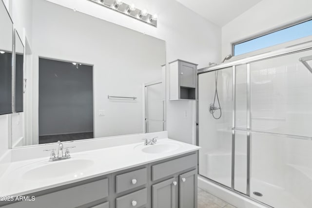 bathroom featuring a stall shower, double vanity, and a sink