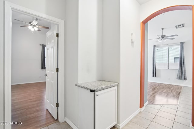 corridor featuring visible vents, baseboards, and light tile patterned floors