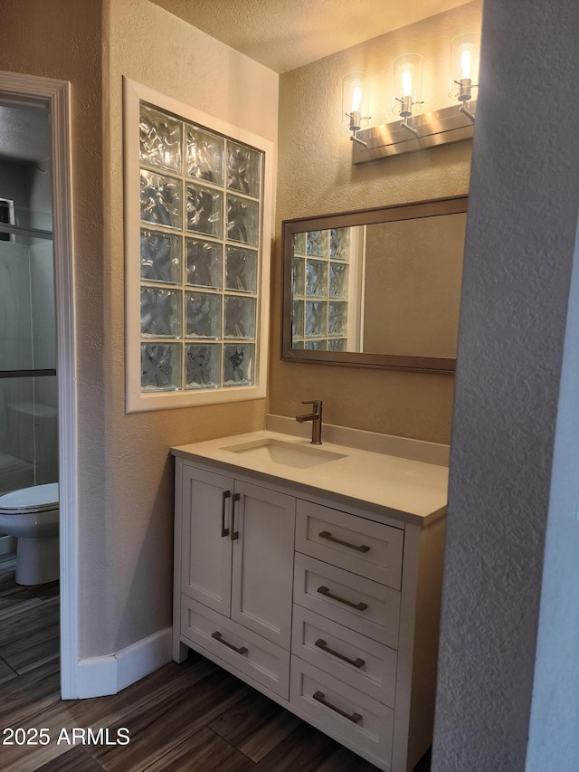 2105 W Terrace Dr, Wickenburg, AZ 85390 - bathroom with wood finished floors, vanity, toilet, a textured wall, and a shower with door