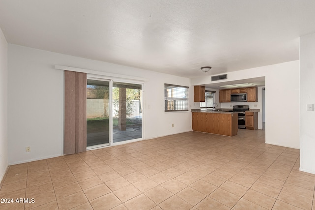 unfurnished living room featuring light tile patterned floors and sink