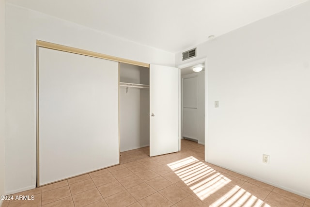 unfurnished bedroom with light tile patterned flooring and a closet