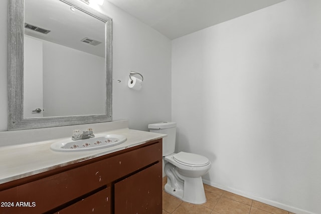 bathroom with toilet, vanity, and tile patterned floors