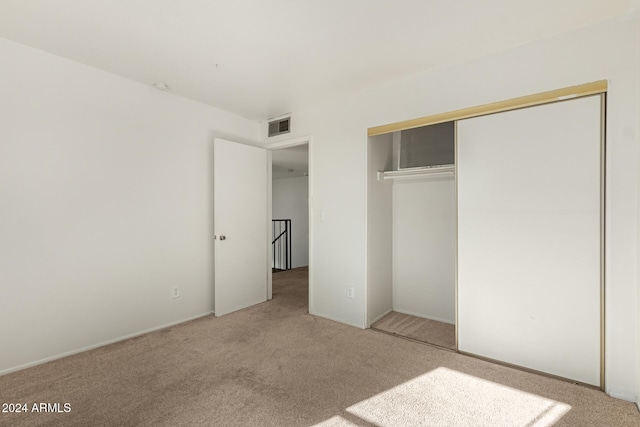 unfurnished bedroom with a closet and light colored carpet