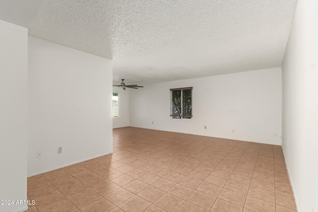 empty room featuring light tile patterned flooring, ceiling fan, and a textured ceiling