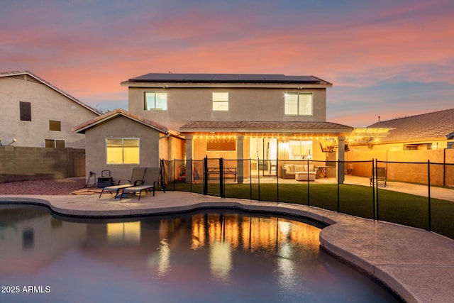 pool at dusk featuring a patio and a lawn