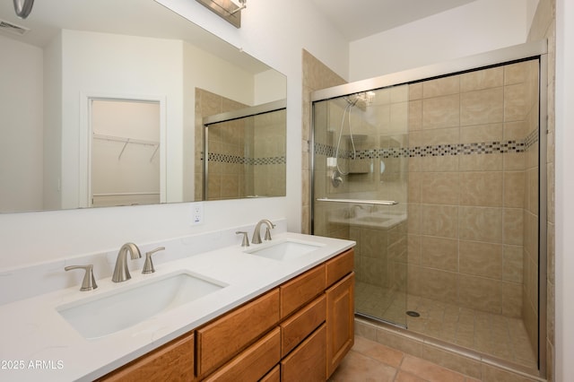 bathroom featuring double vanity, a stall shower, a sink, and visible vents