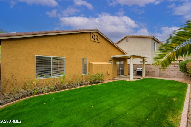 back of property with a patio, a lawn, fence, and stucco siding