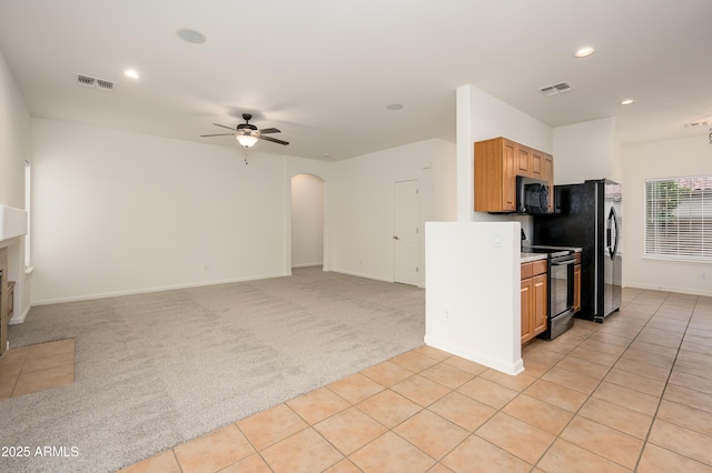 kitchen with light colored carpet, visible vents, arched walkways, and black appliances