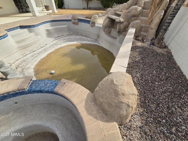 view of swimming pool featuring fence and an empty pool