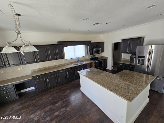 kitchen with a center island, visible vents, appliances with stainless steel finishes, a sink, and dark cabinetry