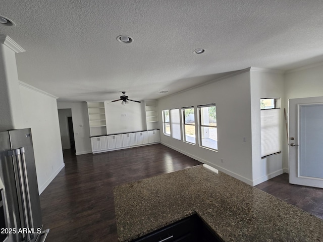 unfurnished living room with dark wood-style floors, a textured ceiling, baseboards, and crown molding