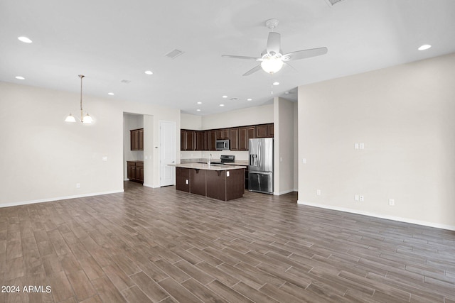 kitchen with dark brown cabinets, ceiling fan with notable chandelier, light hardwood / wood-style floors, appliances with stainless steel finishes, and a kitchen island with sink